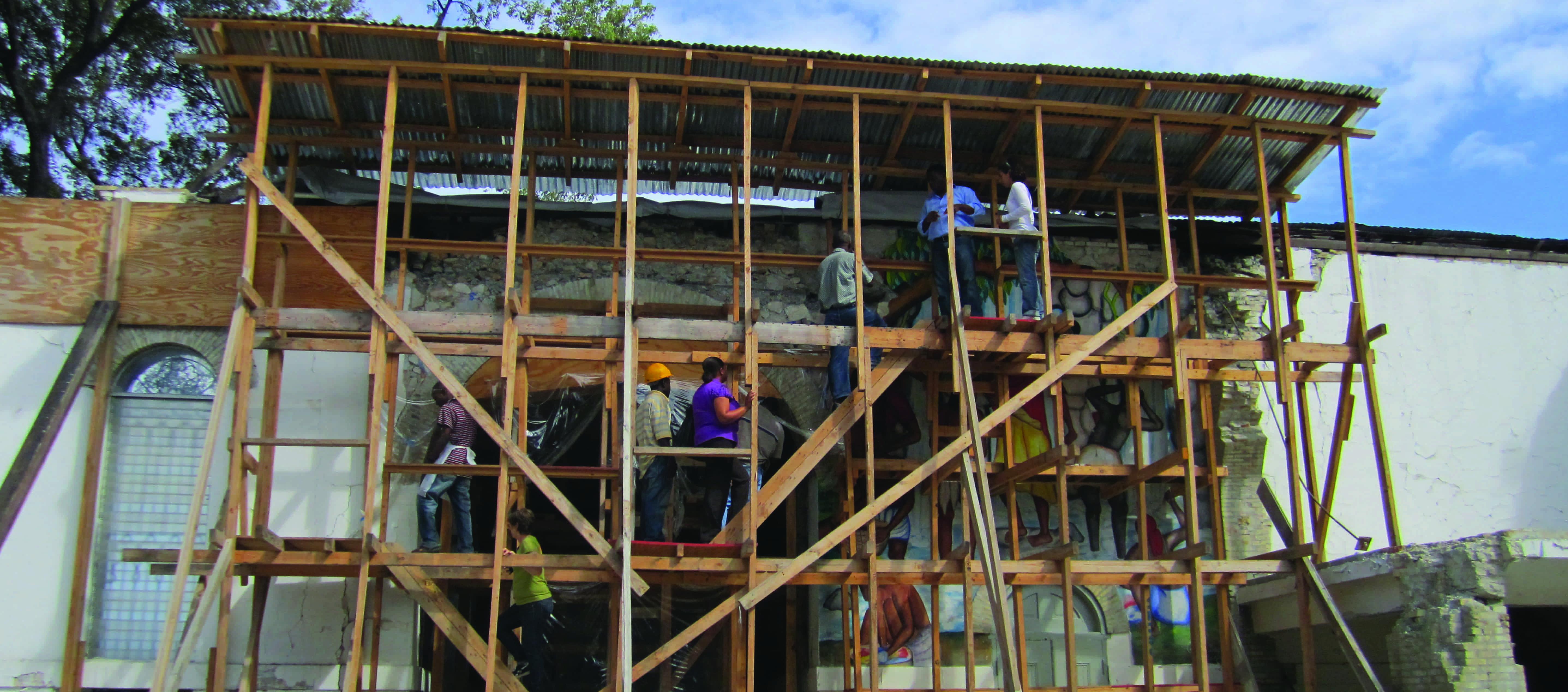 Scaffolding covers the front of a building in Haiti pile of rocks in foreground 