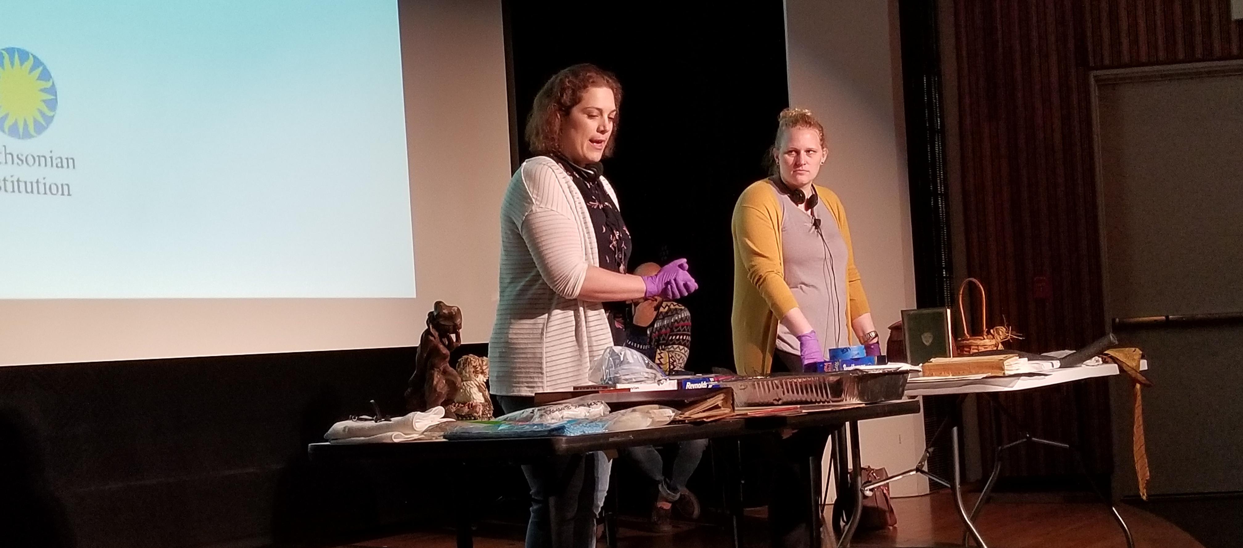 Two women stand present salvage techniques on stage