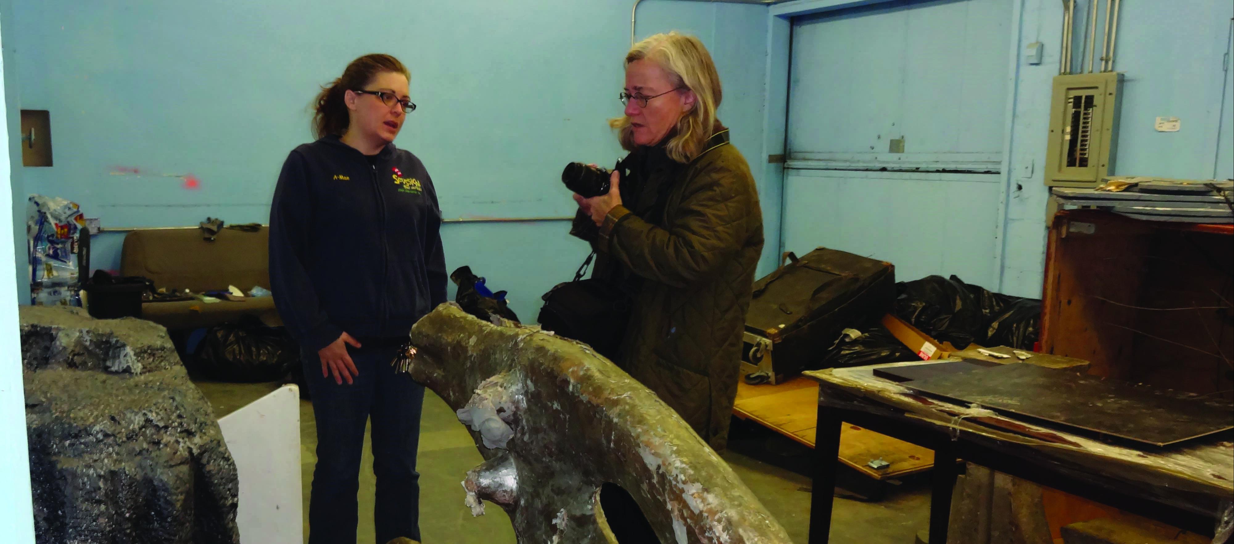 two women stand next to a large obejct