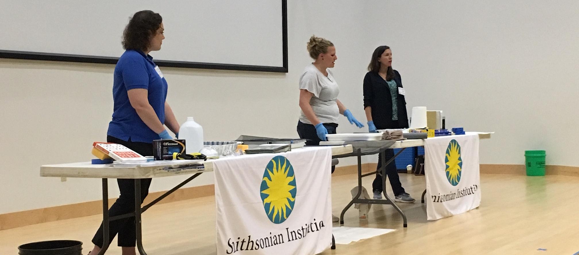 three women present object salvage techniques on a stage