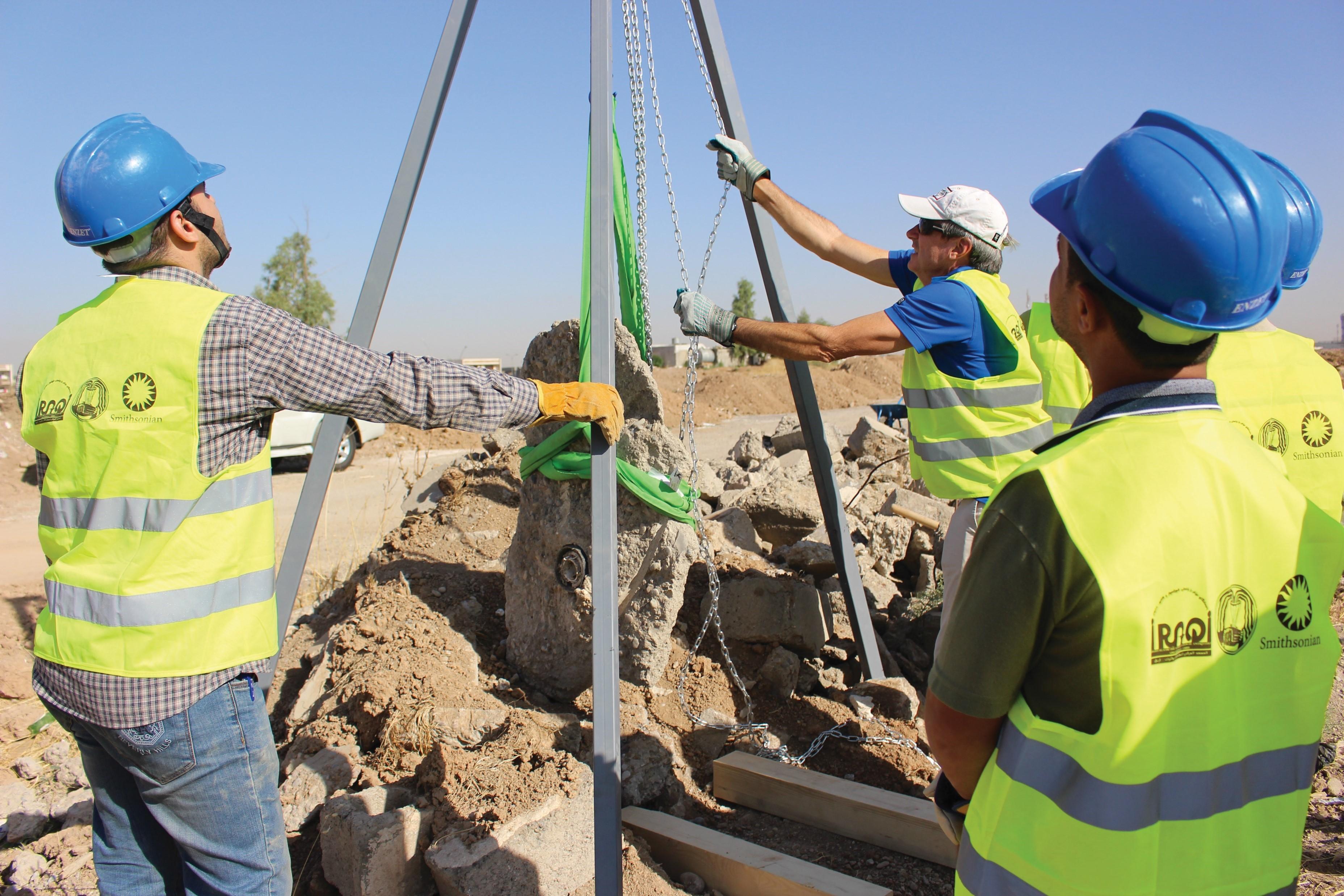 Smithsonian-Iraqi team prepares for the Nimrud recovery operation. 3 men in yellow vests and blue hardhats