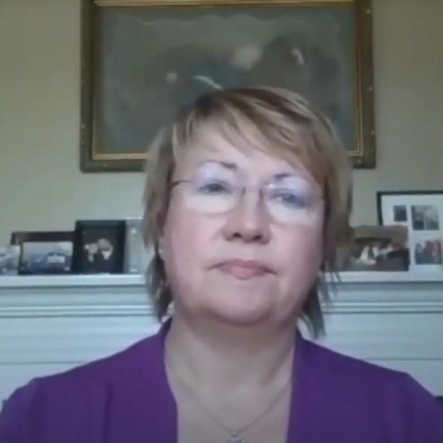 woman with short blond hair and glasses wearing a purple shirt