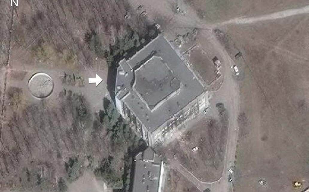 Satellite image of the University (dated 29 March 2022). Fire damage and scorch marks on the building’s exterior walls and debris around the site are visible. Scale: 30m. Arrow points to the main University building. Source: © 2024 MAXAR.
