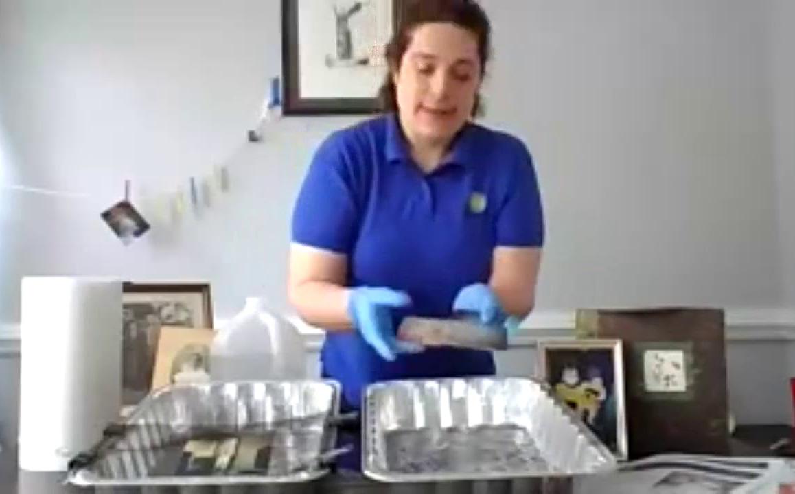 Woman in blue shirt holds a water damaged book over a disposable turkey pan