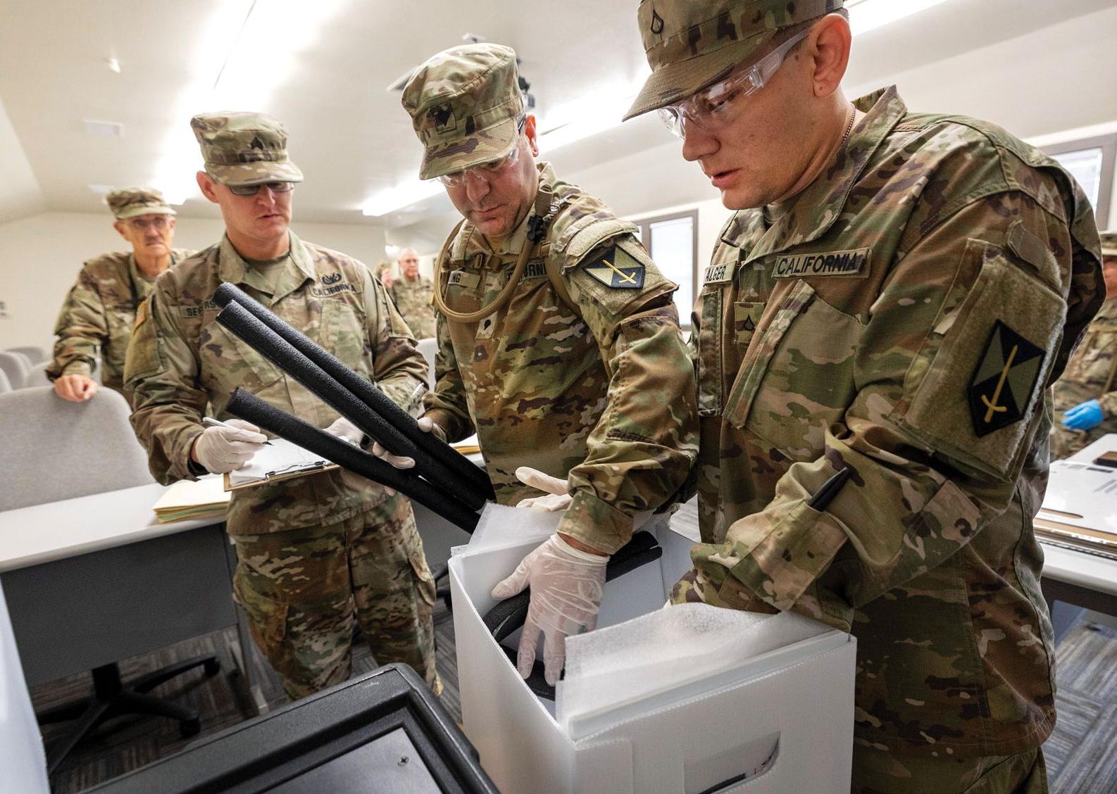 men in miliary camouflage handle objects