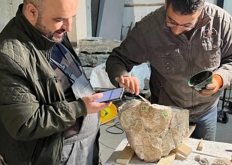 two men looking at stone object