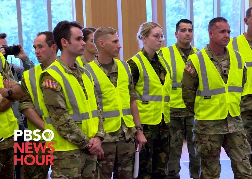 Men and Women in military uniform and yellow vests stand together