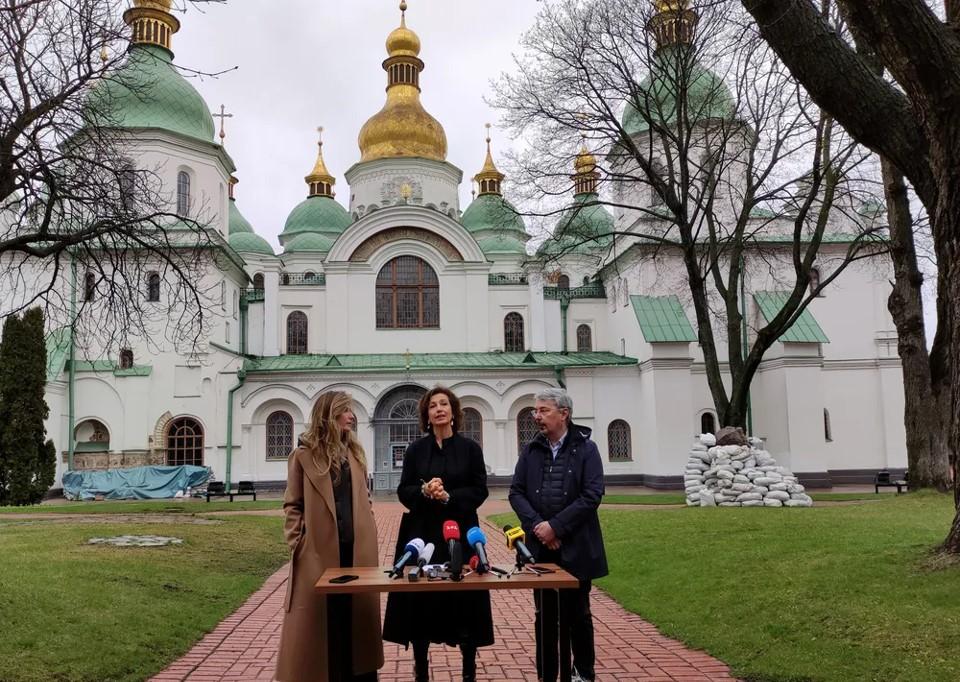 two women and a man in front of a Ukrainian church with green roof and gold dome